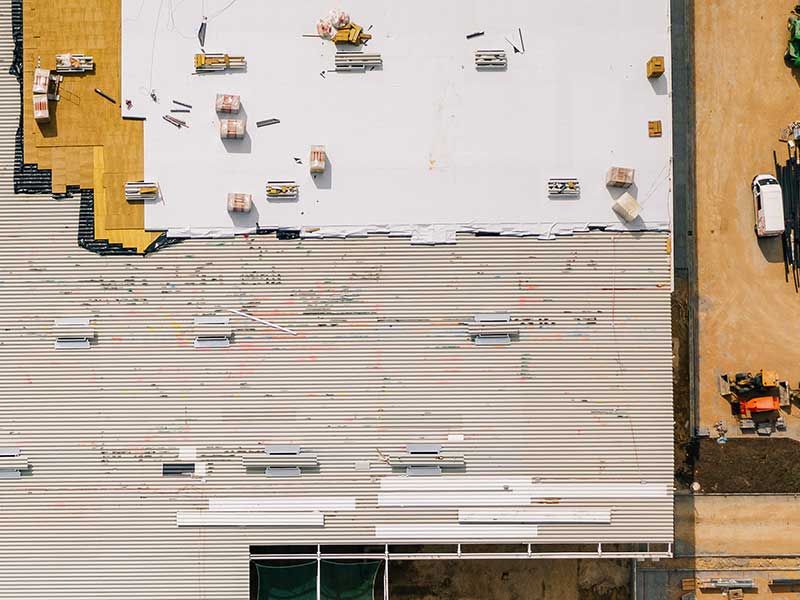 Bird-eye view of a new commercial building getting a white TPO system installed
